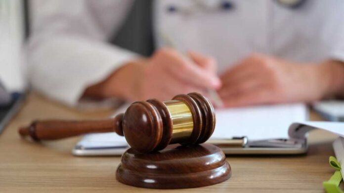 Wooden,Gavel,Of,Judge,On,Table,Close-up,,And,Blurred,Doctor