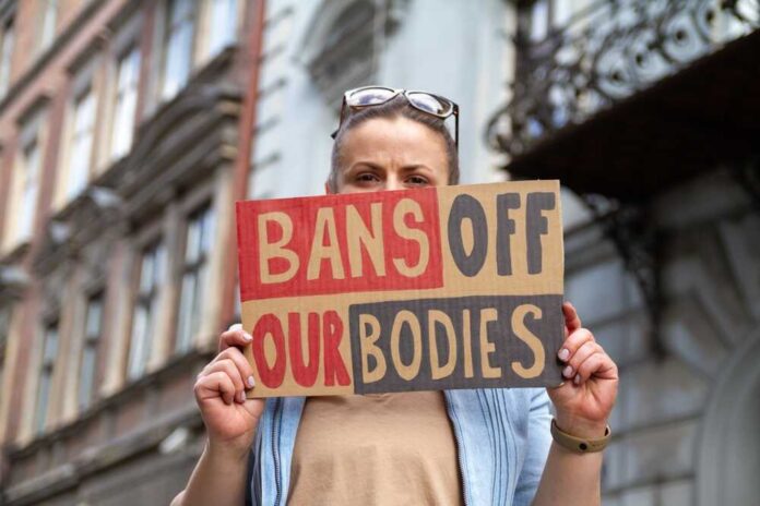 Woman,Holding,Sign,With,Slogan,Bans,Off,Our,Bodies.,Protester