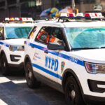 Parked row of NYPD police vehicles with flashing lights.