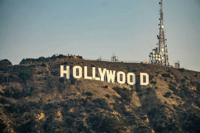 Hollywood sign with communication tower on hillside.