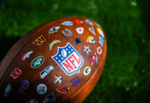 NFL football with team logos on grass field.