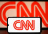 SCANDAL: CNN’s Silence Amid Internal Revolt CNN logo on phone and screen background.