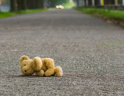 Teddy bear lying on an empty road.