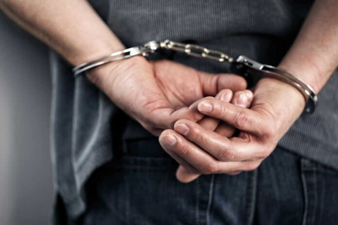 Person handcuffed with hands behind back.
