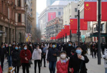 Crowded street with people wearing masks and flags