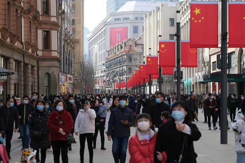 Crowded street with people wearing masks and flags