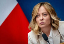 Person speaking at a conference with flag background