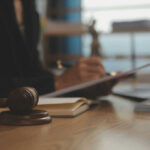 gavel on table, person with pen writing