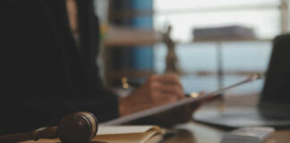 gavel on table, person with pen writing
