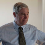 A business professional in a light blue shirt and tie, engaged in conversation