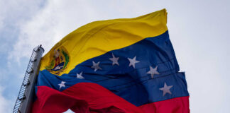 Venezuelan flag waving against a cloudy sky