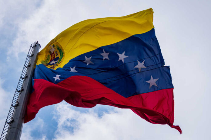 Venezuelan flag waving against a cloudy sky