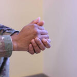 Close-up of a soldier's hands clasped together in a thoughtful pose