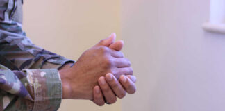 Close-up of a soldier's hands clasped together in a thoughtful pose
