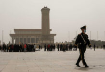 A military guard walking past a crowd at Tiananmen Square in foggy conditions