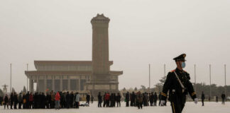 A military guard walking past a crowd at Tiananmen Square in foggy conditions