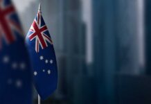 Athlete Asylum Drama: Iran’s Grip Tightens Australian flag displayed on a flagpole with a blurred city background