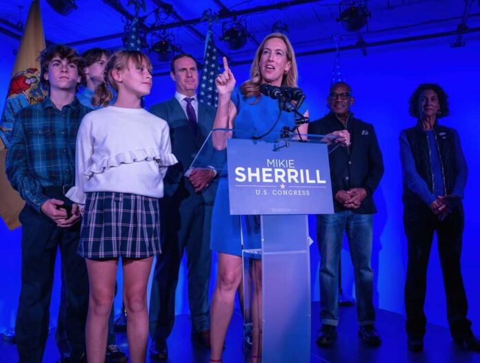 A female politician delivering a speech at a podium with supporters behind her