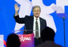 A speaker waving at an audience during a conference