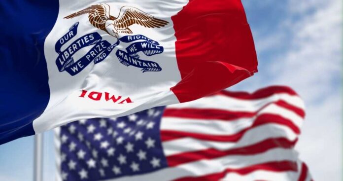 shutterstock_2392504825.jpg Iowa state flag in front of the American flag, both waving in the wind