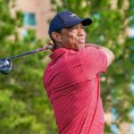 Golfer in a red striped shirt swinging a golf club