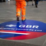 A construction worker walking over a circular railway logo on the ground