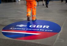 A construction worker walking over a circular railway logo on the ground