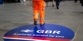 A construction worker walking over a circular railway logo on the ground
