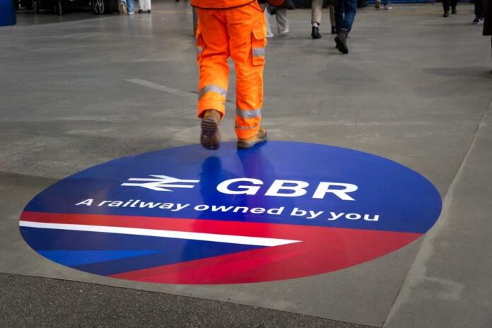 A construction worker walking over a circular railway logo on the ground