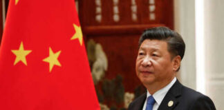Man in suit standing next to Chinese flag