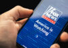 Hand holding smartphone showing Fox News Channel logo.