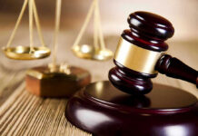 Wooden gavel and scales of justice on table