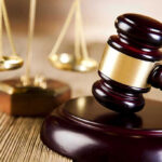 Wooden gavel and scales of justice on table