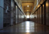 Empty prison corridor with metal cell doors visible