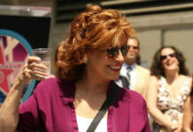 Woman smiling holding a cup with people in background