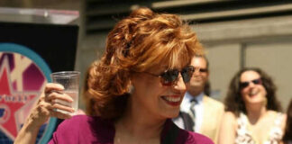 Woman smiling holding a cup with people in background