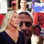 Woman speaking with people holding political signs background