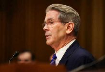 Man in suit speaking at a microphone indoors