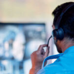 Person with headset monitoring multiple screens
