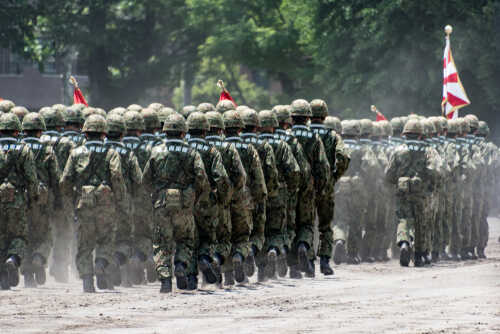 Soldiers in camouflage uniforms marching in formation during a military parade