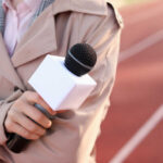 A reporter holding a microphone on a running track