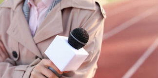 A reporter holding a microphone on a running track