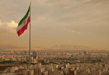 Iran’s Navy in RUINS – Media SILENT! Iranian flag waving over a city skyline with mountains in the background