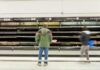 A man stands in front of empty meat shelves in a grocery store