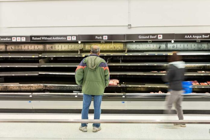 A man stands in front of empty meat shelves in a grocery store