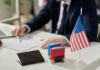 A professional reviewing documents with stamps and an American flag on the table