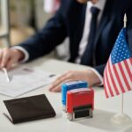 A professional reviewing documents with stamps and an American flag on the table