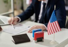 A professional reviewing documents with stamps and an American flag on the table