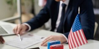 A professional reviewing documents with stamps and an American flag on the table