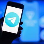 A smartphone displaying the Telegram logo against a blue background